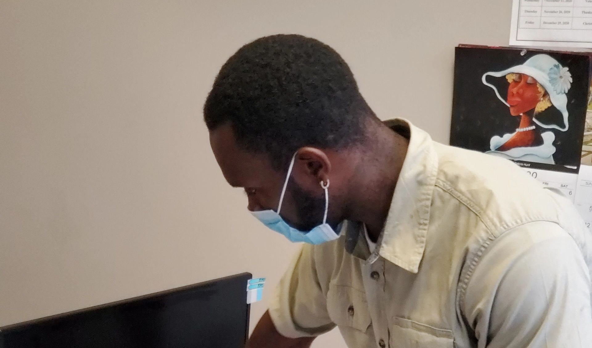 A uniformed cleaner working at an office workstation